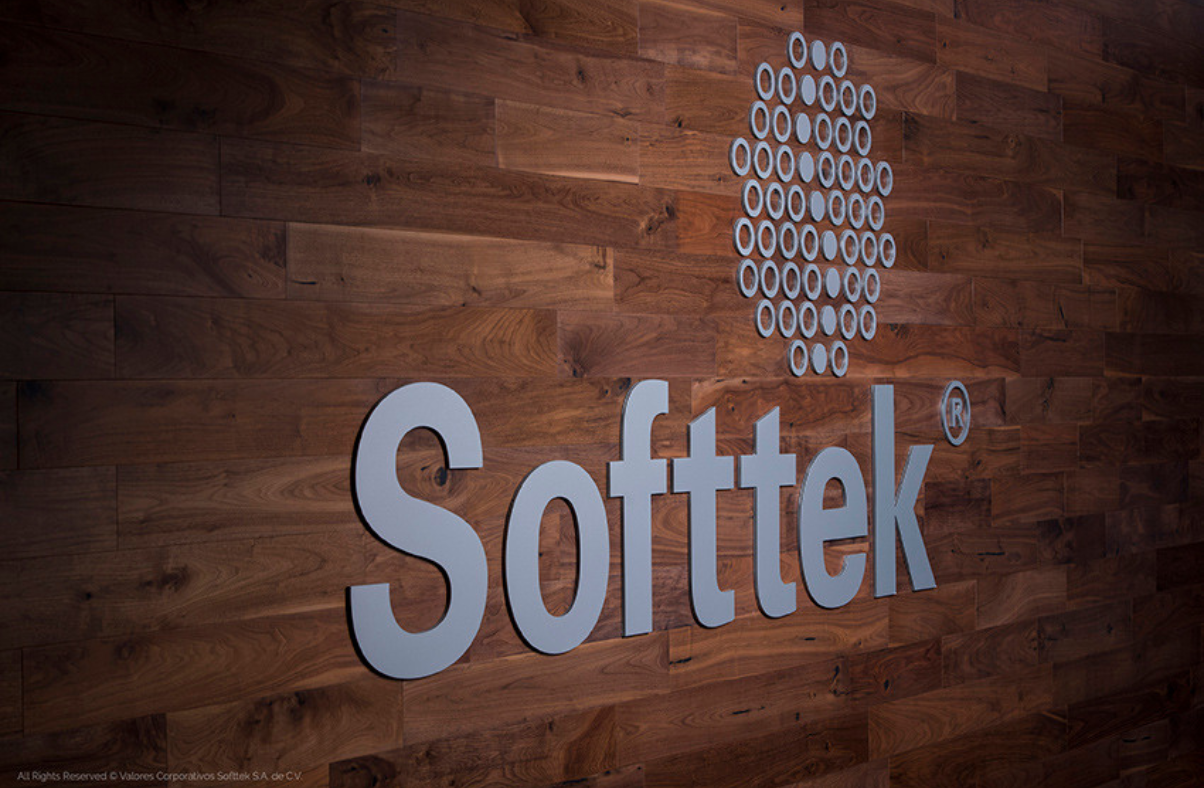 Close-up of the Sofftek logo in metallic letters mounted on a wood-paneled wall.