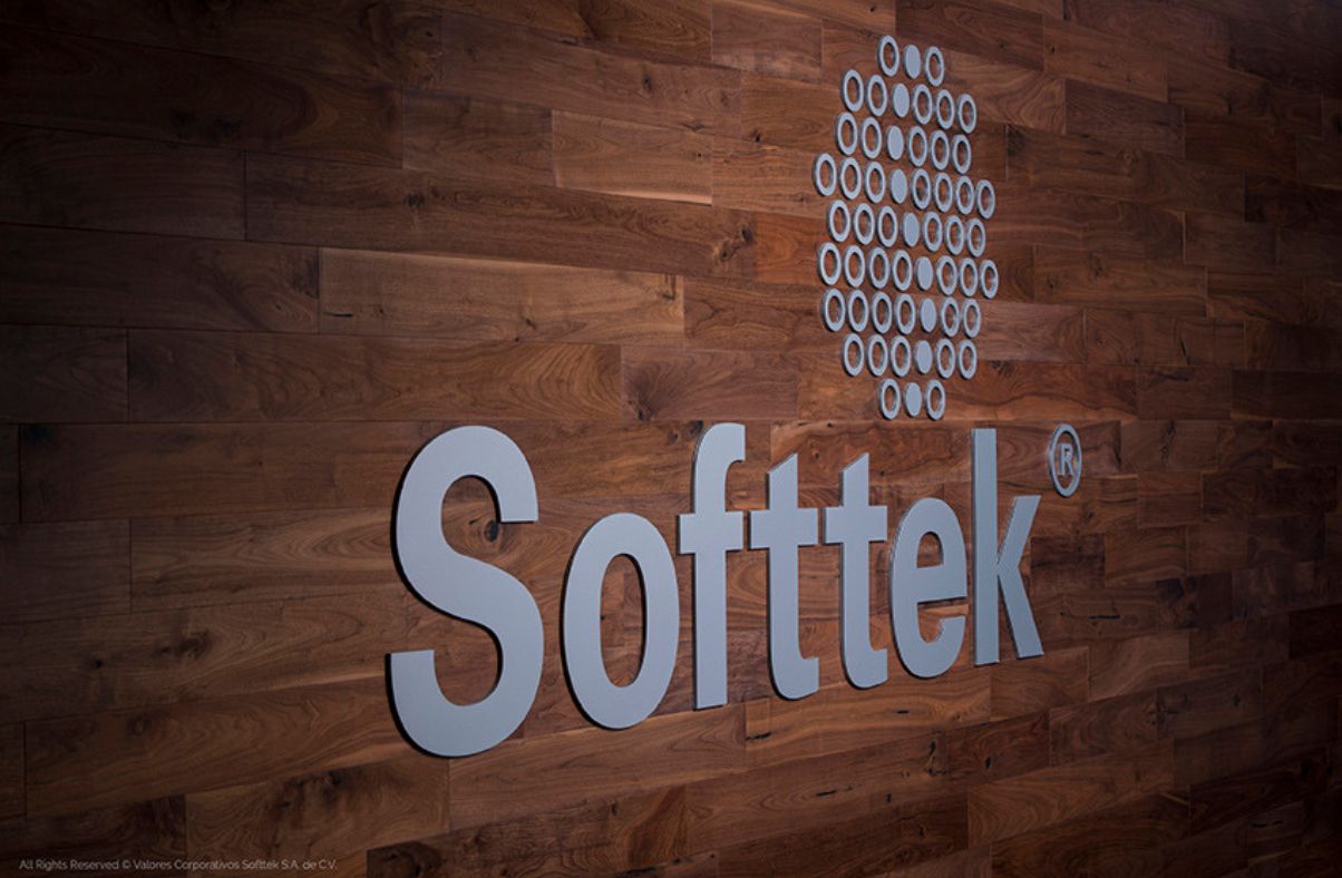 Softtek company logo mounted on a wooden wall.