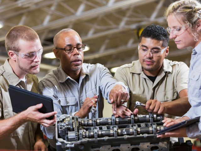 Vocational students collaborate on a hands-on mechanical training exercise, demonstrating teamwork and practical skills development in a learning environment.