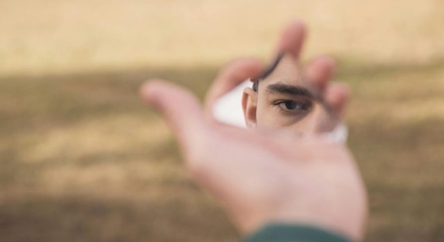 Person looking through their hand, with only part of their face in focus.