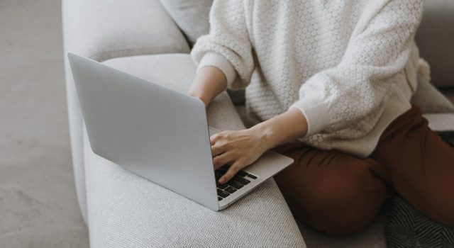 Person working on a laptop while sitting on a sofa
